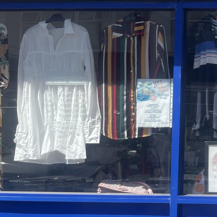 A white cotton shirt and a striped shirt hanging in the shop window